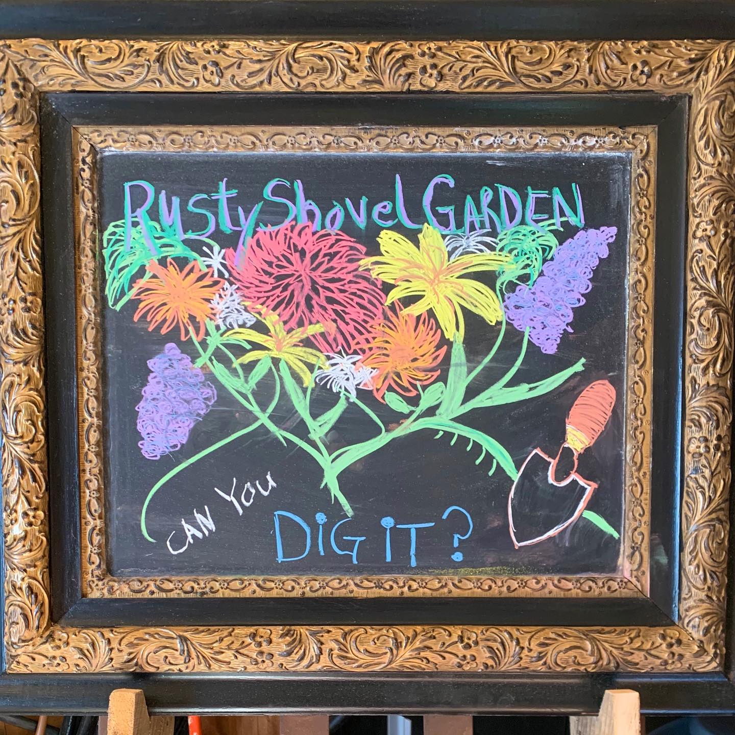 chalkboard with flower drawning and says rusty shovel gardens